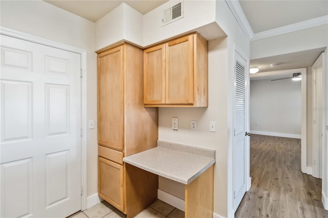 kitchen with visible vents, baseboards, light countertops, ornamental molding, and light brown cabinetry