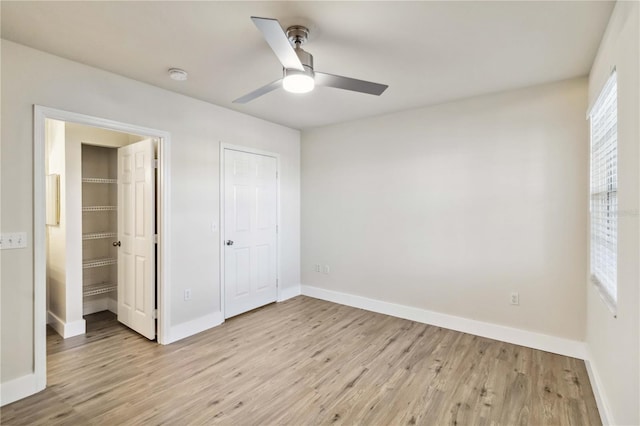 unfurnished bedroom featuring light wood-style flooring, baseboards, and a ceiling fan