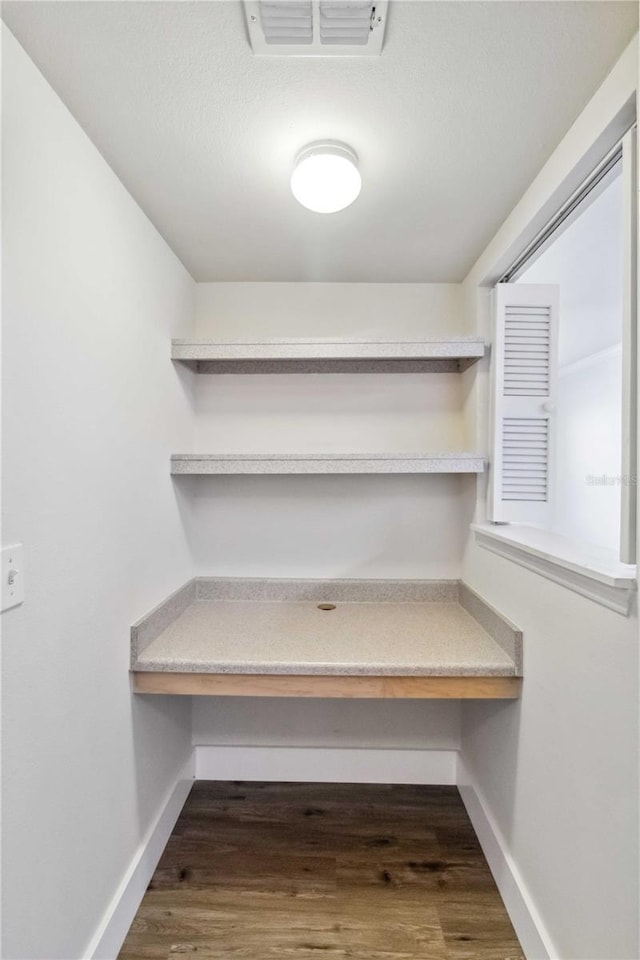 interior space featuring visible vents, dark wood finished floors, and built in desk