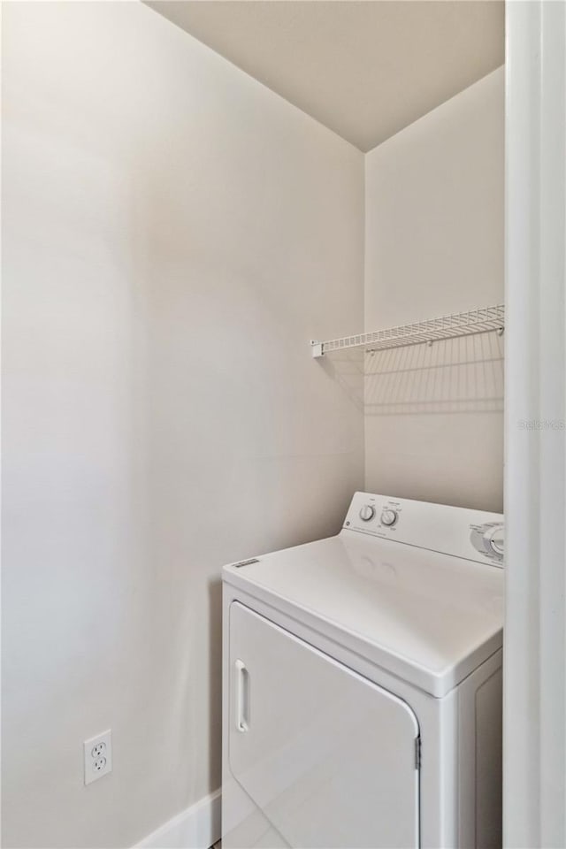 clothes washing area with laundry area, washer / clothes dryer, and baseboards