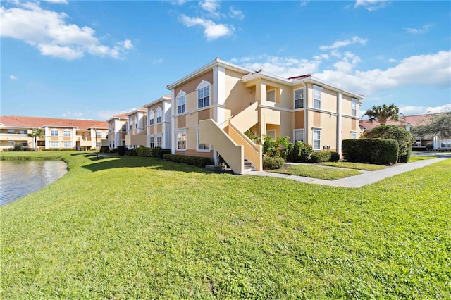 view of building exterior featuring a water view, a residential view, and stairway