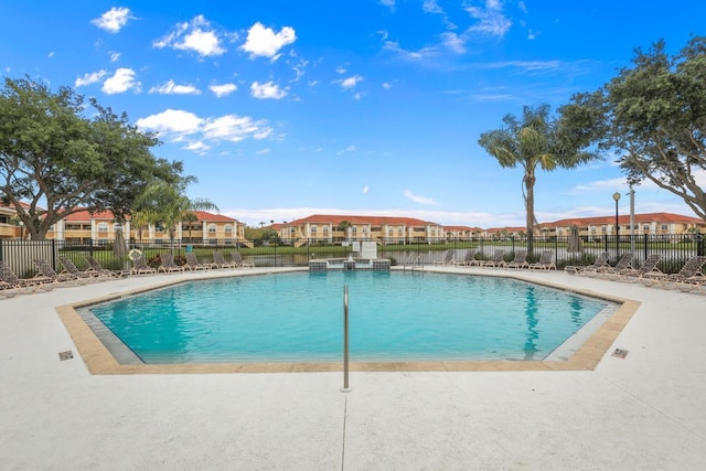 pool with a patio, fence, and a residential view