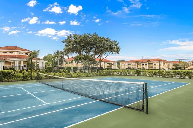 view of tennis court with a residential view and fence