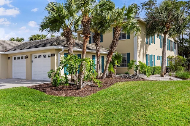 view of front of property with a front lawn, a garage, driveway, and stucco siding