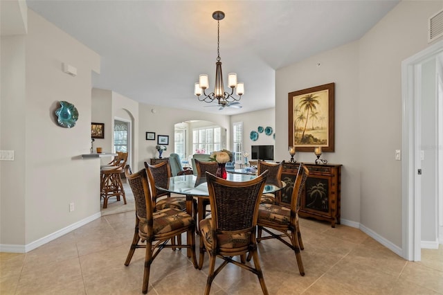 dining area featuring light tile patterned flooring, baseboards, arched walkways, and a chandelier