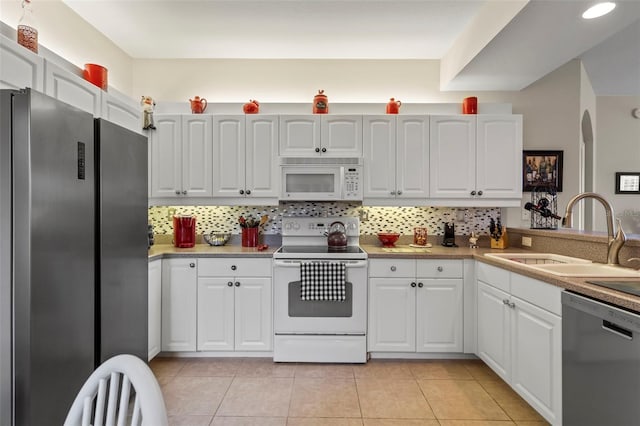 kitchen featuring decorative backsplash, light tile patterned flooring, white cabinets, stainless steel appliances, and a sink