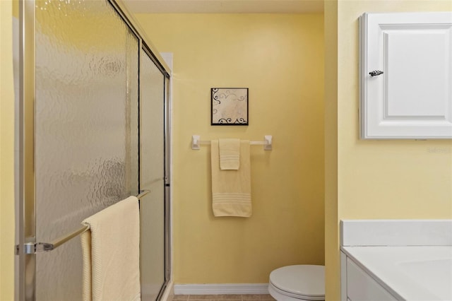 bathroom with baseboards, toilet, a stall shower, and vanity