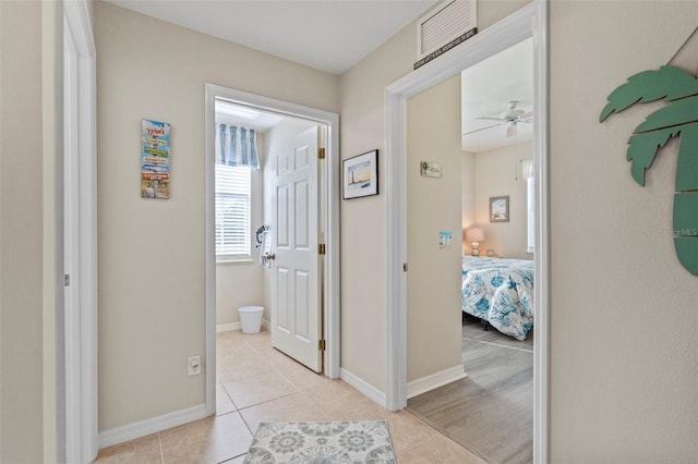 hallway featuring light tile patterned floors, visible vents, and baseboards