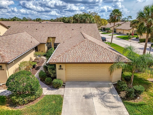 view of front of house with a shingled roof, concrete driveway, an attached garage, and stucco siding