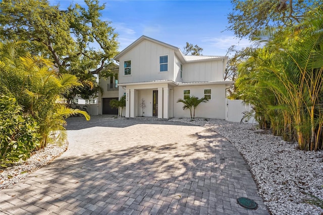 view of front of home with a gate, fence, decorative driveway, board and batten siding, and metal roof