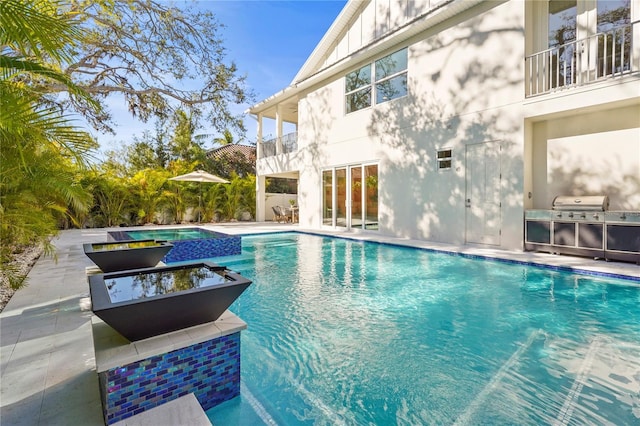 view of swimming pool featuring area for grilling, a pool with connected hot tub, and a patio