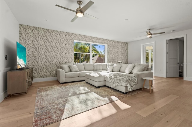 living area featuring wallpapered walls, light wood-style flooring, and baseboards