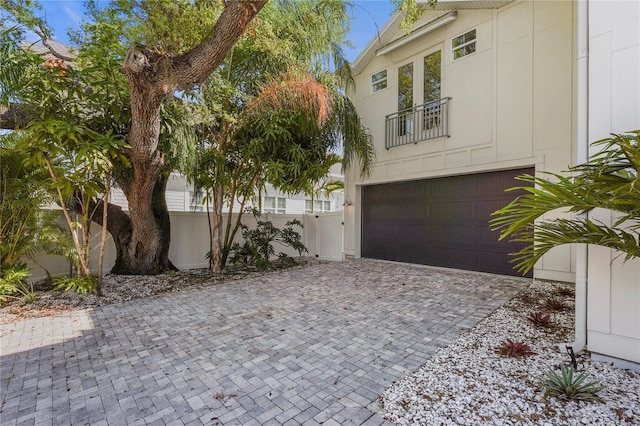 view of front facade with decorative driveway, a garage, and fence