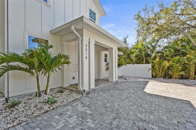 doorway to property featuring a patio area, fence, and board and batten siding