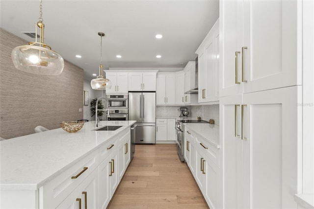 kitchen with high quality appliances, a sink, white cabinetry, recessed lighting, and light wood finished floors