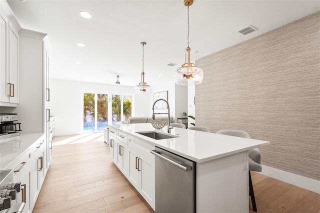 kitchen with an accent wall, visible vents, wallpapered walls, a sink, and stainless steel dishwasher