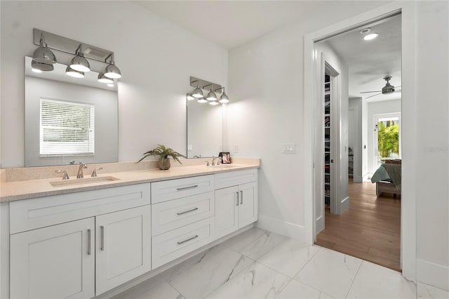 bathroom with double vanity, baseboards, marble finish floor, and a sink