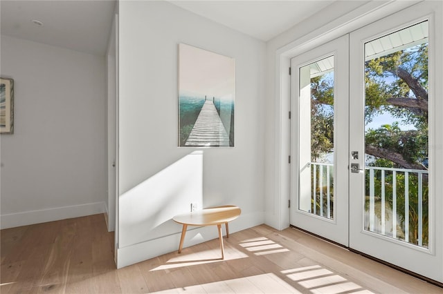 doorway with french doors, baseboards, and wood finished floors