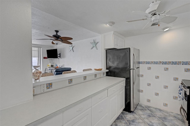 kitchen with tile walls, ceiling fan, a textured ceiling, appliances with stainless steel finishes, and white cabinets