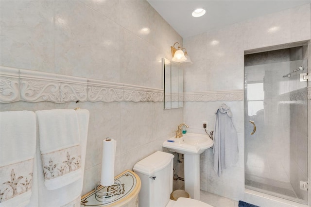 bathroom with sink, toilet, tile walls, and a shower with shower door