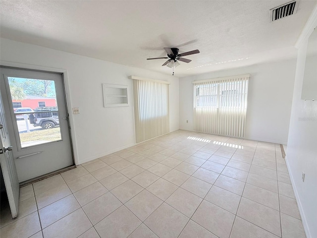 spare room featuring a textured ceiling, ceiling fan, and light tile patterned floors