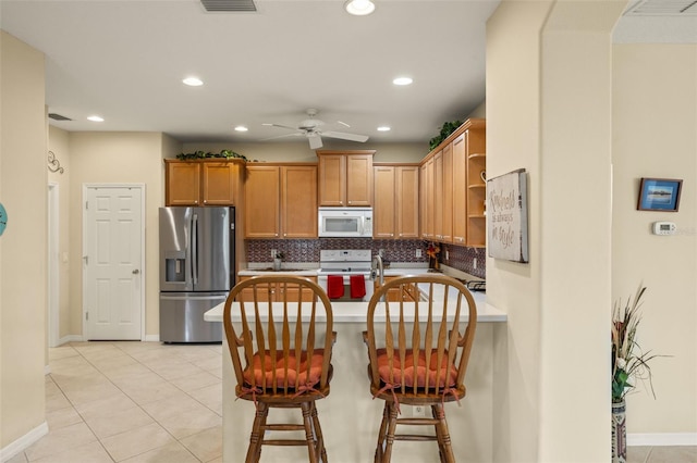 kitchen with a breakfast bar area, open shelves, backsplash, brown cabinetry, and white appliances