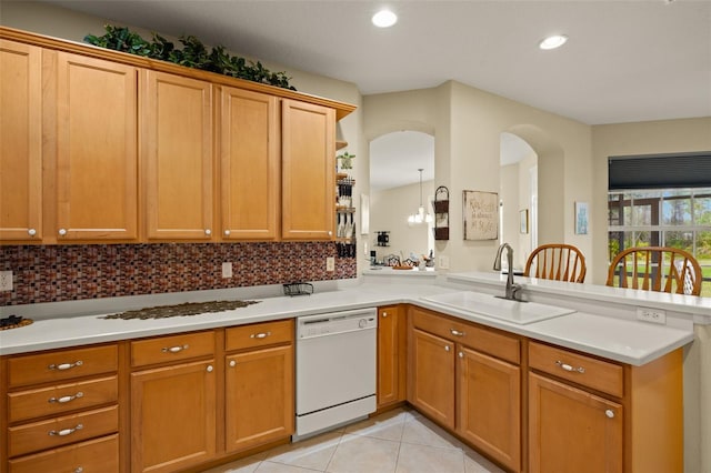 kitchen with light tile patterned floors, dishwasher, a peninsula, light countertops, and a sink