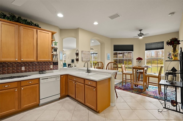 kitchen with a peninsula, white dishwasher, light countertops, open shelves, and a sink