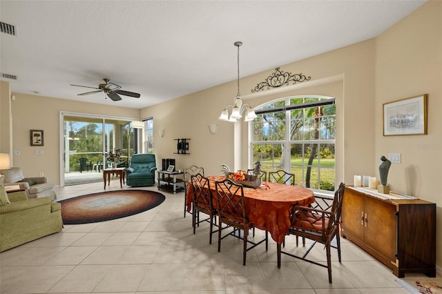 dining space with light tile patterned flooring, visible vents, and ceiling fan with notable chandelier