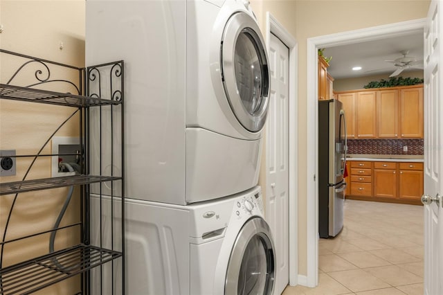 clothes washing area with light tile patterned floors, recessed lighting, a ceiling fan, stacked washer / dryer, and laundry area