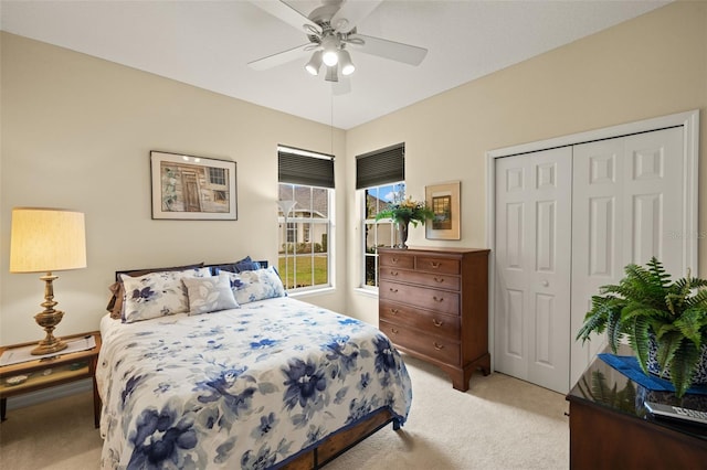 bedroom featuring a ceiling fan, a closet, and light colored carpet