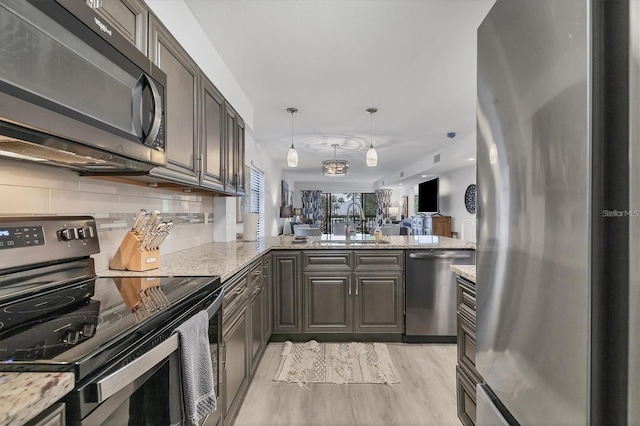 kitchen with appliances with stainless steel finishes, open floor plan, backsplash, and light stone countertops