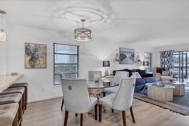 dining area with baseboards, light wood-style flooring, and a notable chandelier