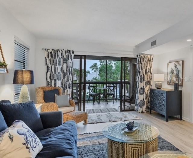 living room featuring wood finished floors, visible vents, and baseboards