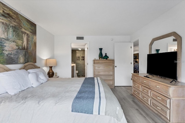 bedroom with light wood finished floors, ensuite bath, and visible vents