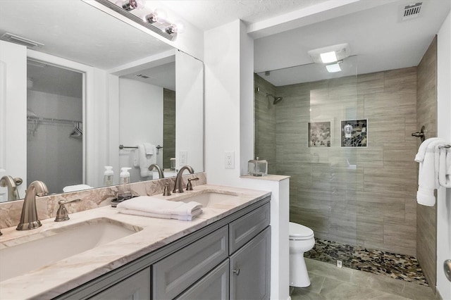 full bath featuring double vanity, visible vents, a walk in closet, and a sink