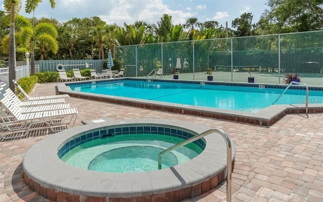 community pool with a tennis court, a community hot tub, and fence