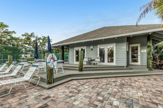 exterior space with french doors, roof with shingles, fence, and a wooden deck