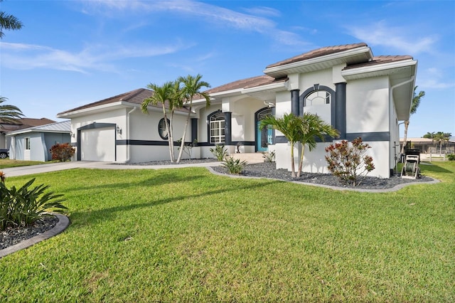 view of front of property featuring driveway, a front lawn, an attached garage, and stucco siding