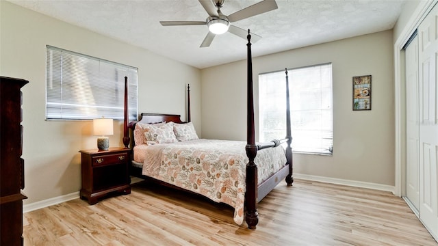 bedroom featuring light wood-type flooring, a closet, ceiling fan, and a textured ceiling