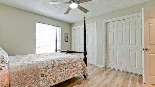 bedroom with light hardwood / wood-style flooring, ceiling fan, a textured ceiling, and two closets