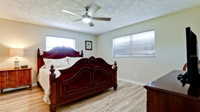 bedroom with light wood-type flooring, a textured ceiling, and ceiling fan