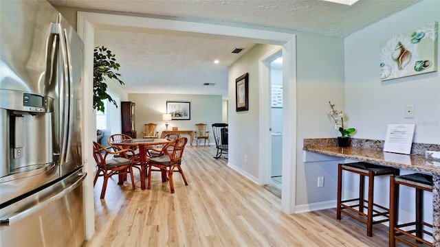 dining space with a textured ceiling and light hardwood / wood-style floors