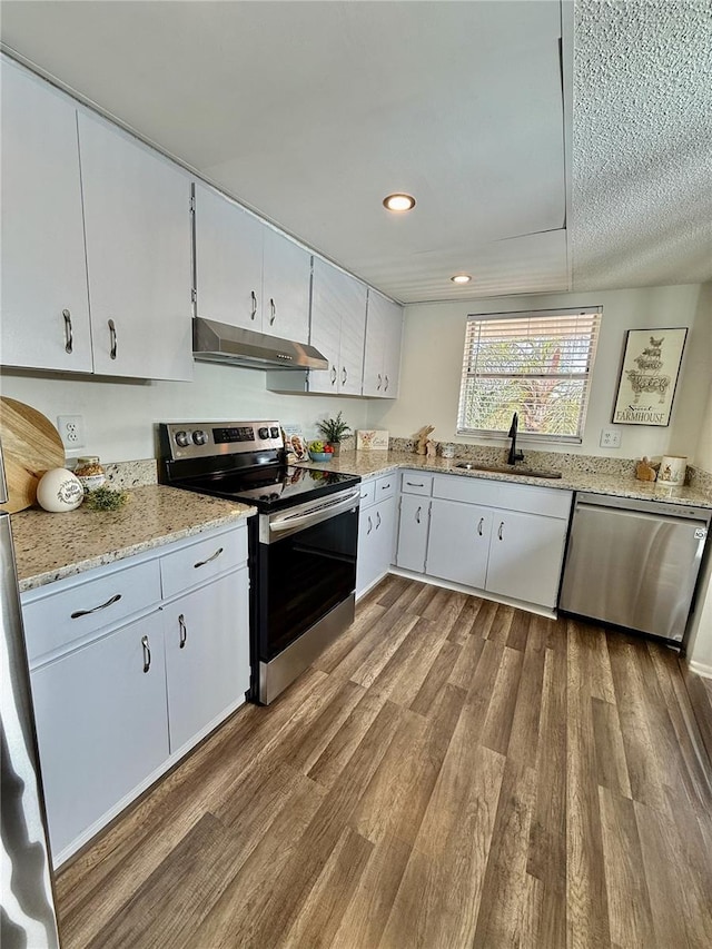 kitchen with sink, light stone counters, light wood-type flooring, stainless steel appliances, and white cabinets