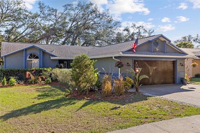 view of front of house with roof with shingles, an attached garage, decorative driveway, a front yard, and stucco siding