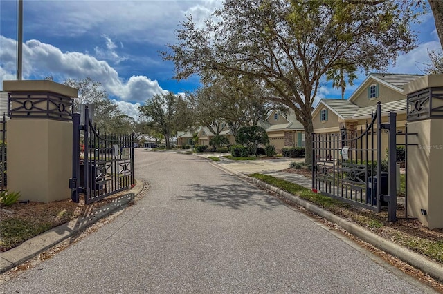 view of street featuring a residential view, a gate, a gated entry, and curbs