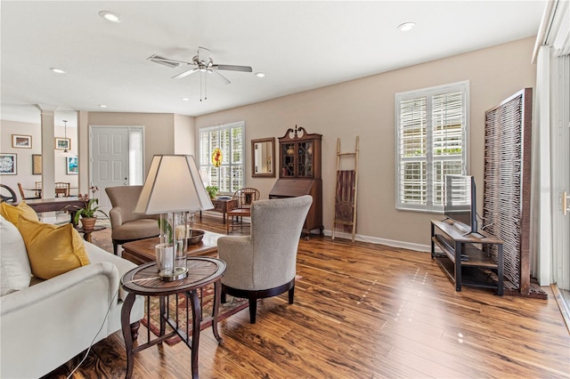 living area with ceiling fan, recessed lighting, wood finished floors, baseboards, and decorative columns