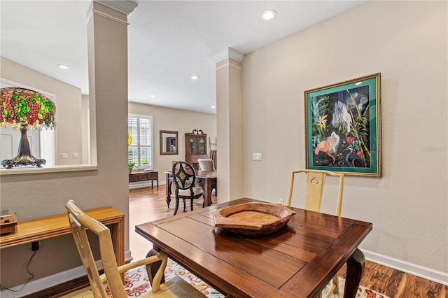 dining space with decorative columns, baseboards, and wood finished floors