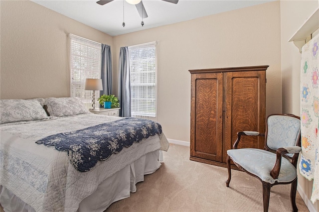 bedroom with light carpet, baseboards, and a ceiling fan