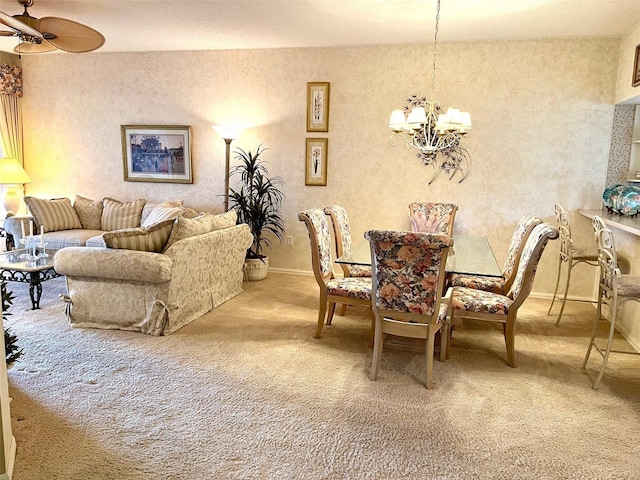 carpeted dining space featuring ceiling fan with notable chandelier and baseboards